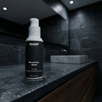 Sharp skincare serum bottle on a dark countertop in a modern bathroom setting